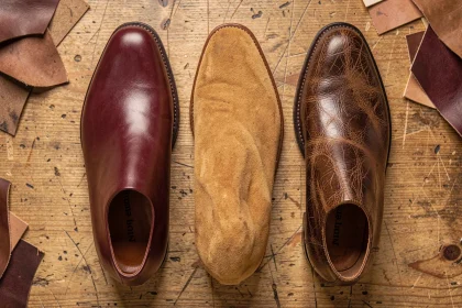 Comparaison de trois types de cuir pour chaussures : cuir lisse, nubuck et cuir gras côte à côte sur bois brut