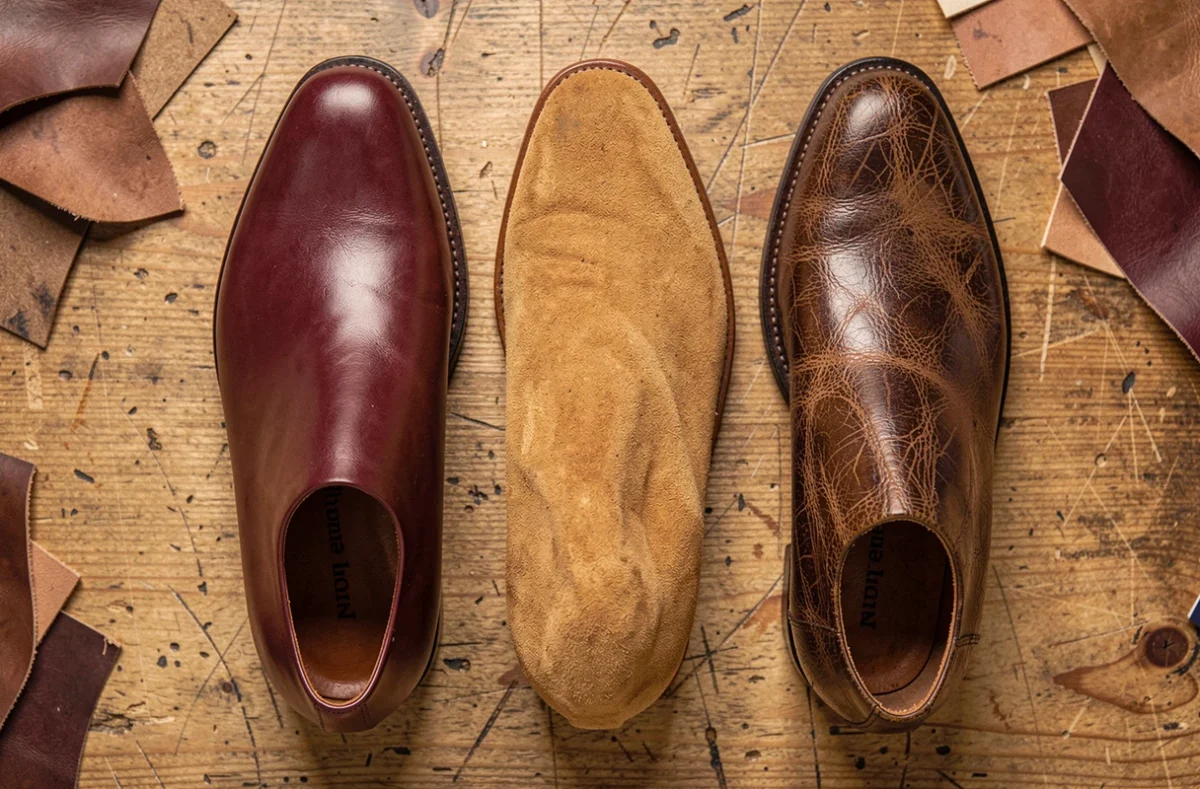 Comparaison de trois types de cuir pour chaussures : cuir lisse, nubuck et cuir gras côte à côte sur bois brut